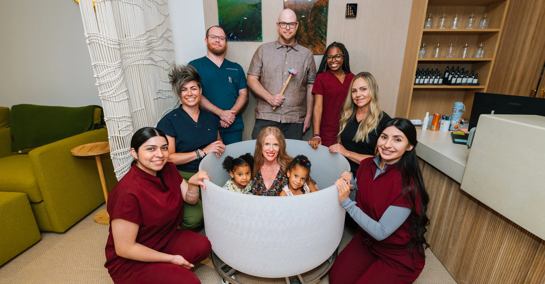 The Lasting Wellness Center care team gathered around a client and two children seated in a large crystal singing bowl in the clinic lounge